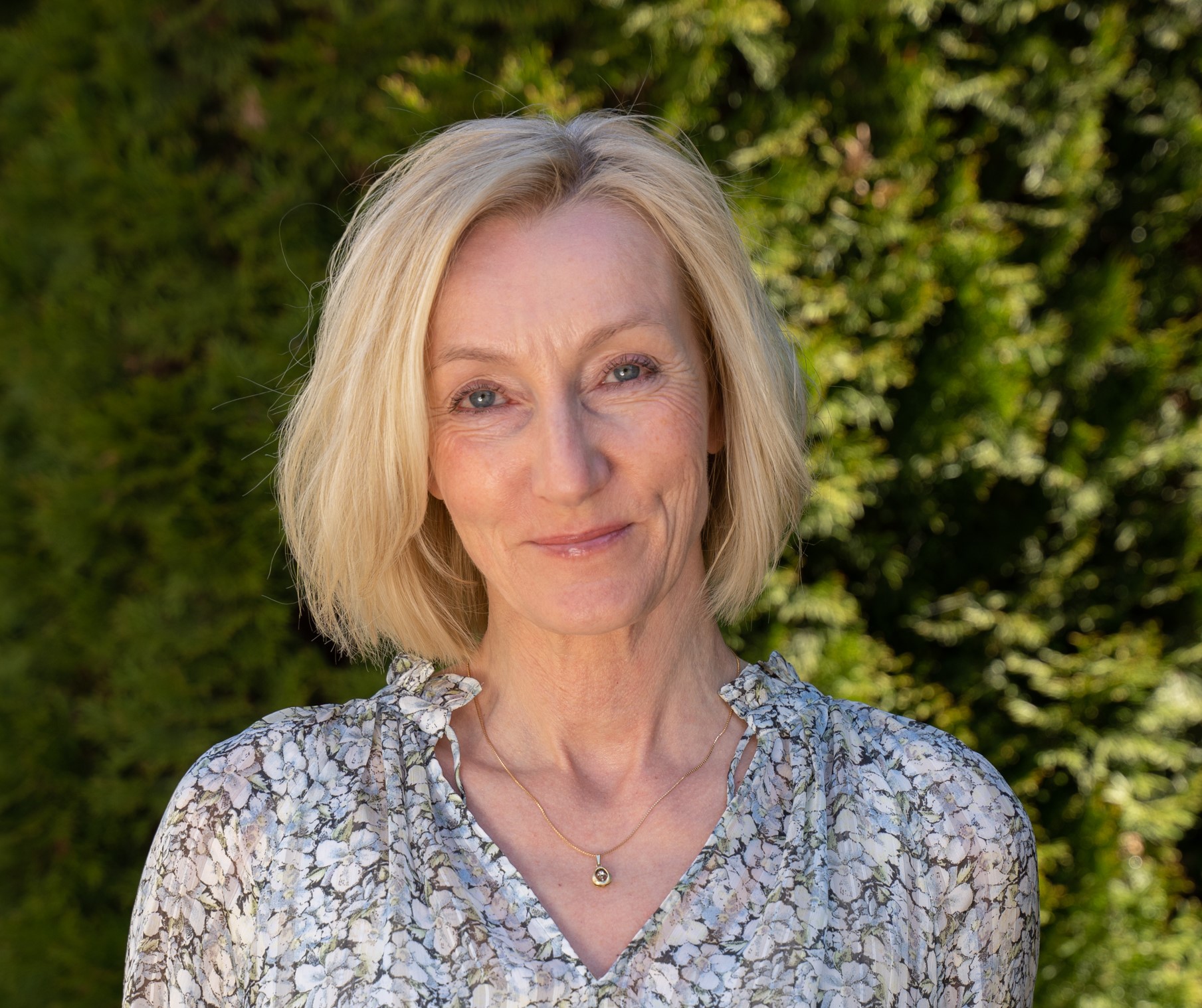 Kvinne med halvlangt blondt hår som smiler. Foto.