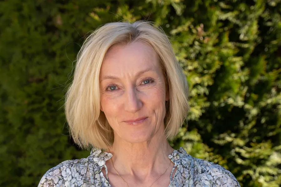 Kvinne med halvlangt blondt hår som smiler. Foto.