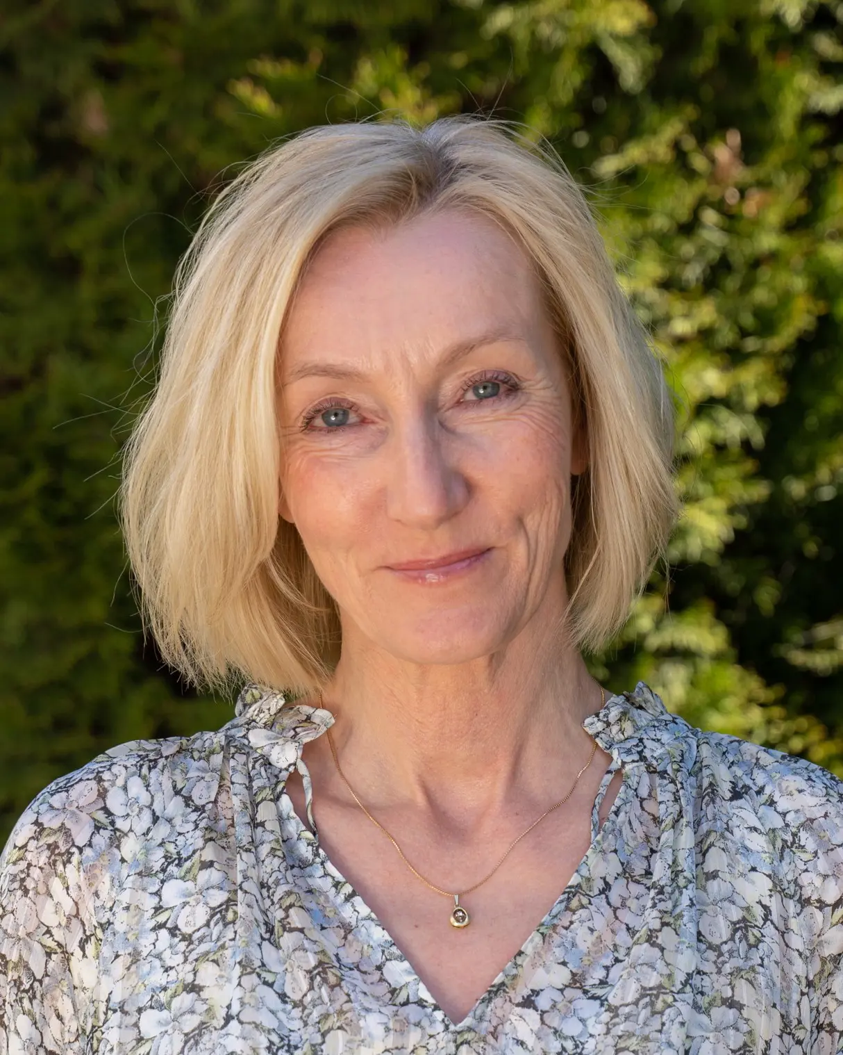 Kvinne med halvlangt blondt hår som smiler. Foto.