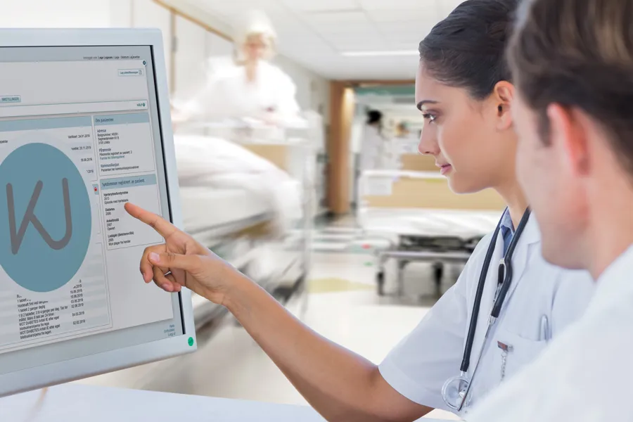 To helsearbeidere ser på en dataskjerm, på et sykehus. Foto.